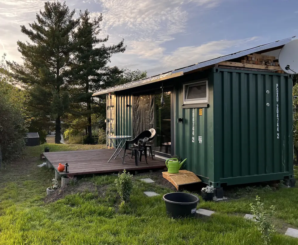 Tiny House aus einem grünen Container mit Holzterrasse